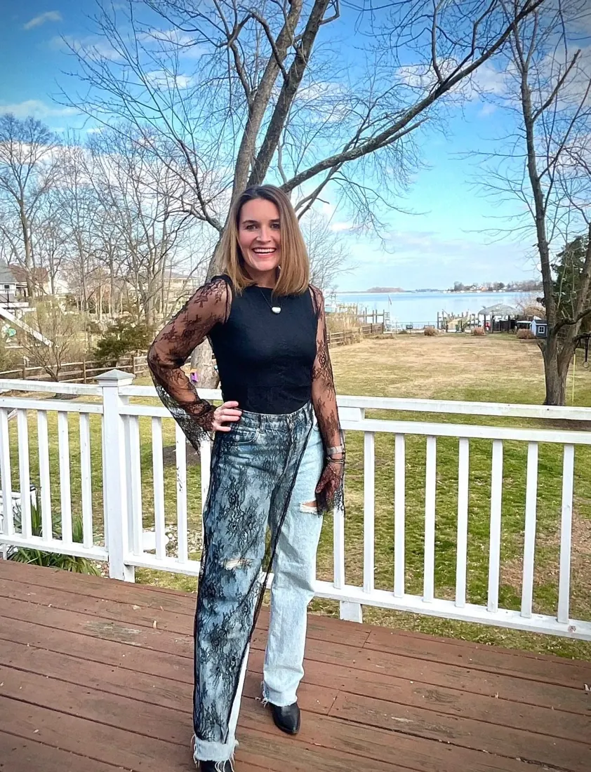 Maggie on her deck in a black lace top layered over jeans